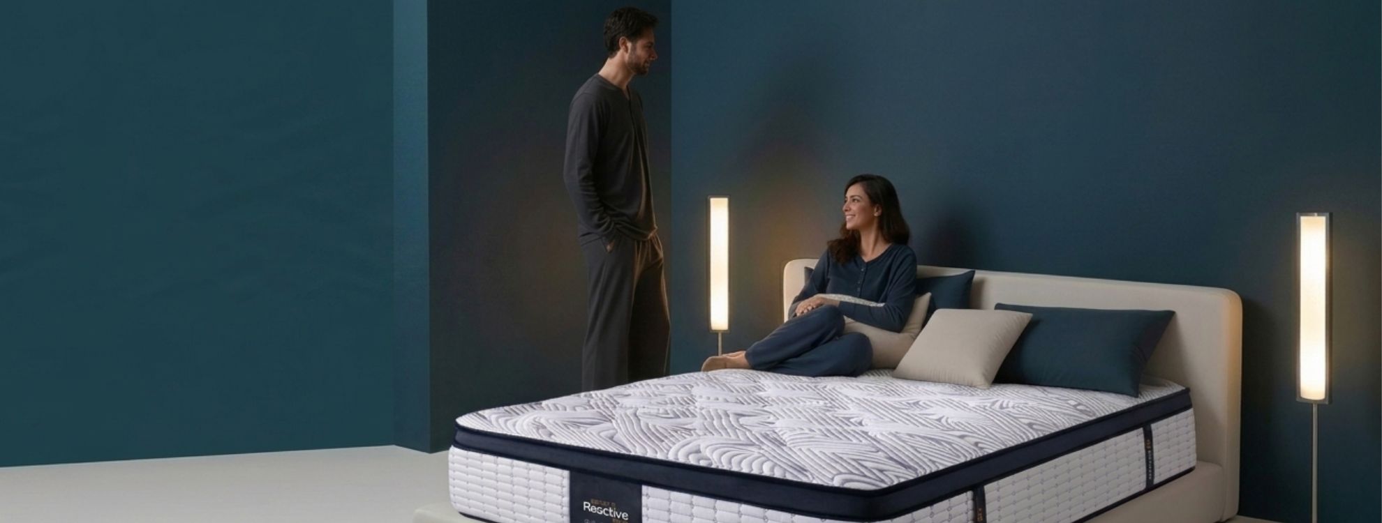 Couple in pajamas relaxing in a teal-toned bedroom with a premium quilted mattress