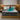 Springfit Club Class Petals luxury mattress lifestyle image with brand ambassador in teal outfit seated on grey scallop-quilted mattress on gold platform bed in elegant bedroom with gold pendant lights and wooden nightstands