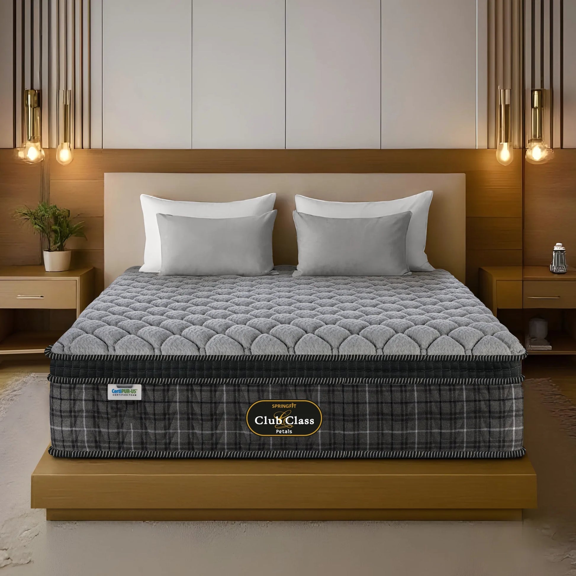 Springfit Club Class Petals mattress on gold platform bed with two white and grey pillow sets in warm luxury bedroom with twin gold filament pendant lights, wooden headboard, and indoor plant