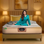 Springfit Emporio Max Latex mattress with GOLS certification on a gold upholstered bed frame with brand ambassador seated in a warm luxury bedroom setting