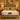 Front view of Springfit Emporio Max Latex mattress with cream velour top and gold accent pillows on a beige bed frame in a luxury golden bedroom