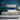 Springfit iSleep Black mattress on a white platform bed with a smiling couple seated together in a vibrant blue-toned modern bedroom