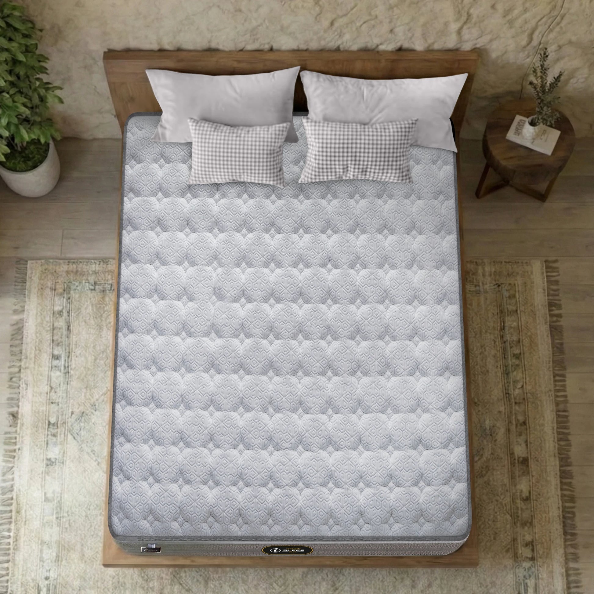 Overhead top-down view of the Springfit iSleep Blue mattress showing its full white diamond and hexagon-quilted surface on a natural wood platform bed with gingham and white pillows