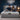 Springfit iSleep Krono mattress on a grey upholstered platform bed with a tall tufted wingback headboard in a navy blue bedroom, with a smiling couple in casual loungewear seated together on the mattress