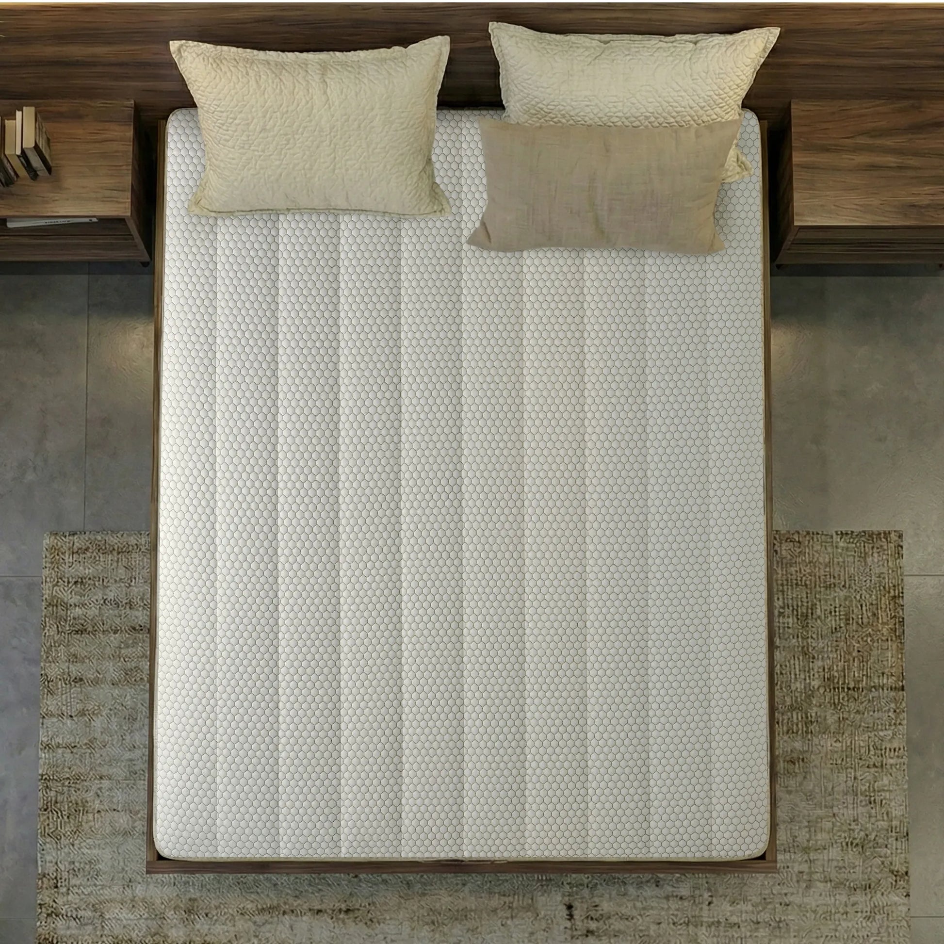 Overhead top-down view of the Springfit iSleep Krono mattress showing its full white honeycomb-textured fabric surface on a dark walnut bed with two cream quilted pillows, set against a grey concrete floor with a patterned rug