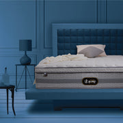 Springfit iSleep Ortho mattress displayed on a blue upholstered bed frame in a moody, dark-blue luxury bedroom with a side table lamp and decorative accents