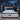 Springfit ProActiv Flow mattress with couple in navy blue outfits in deep blue accent bedroom with wooden headboard, blue cushions, and abstract wall art