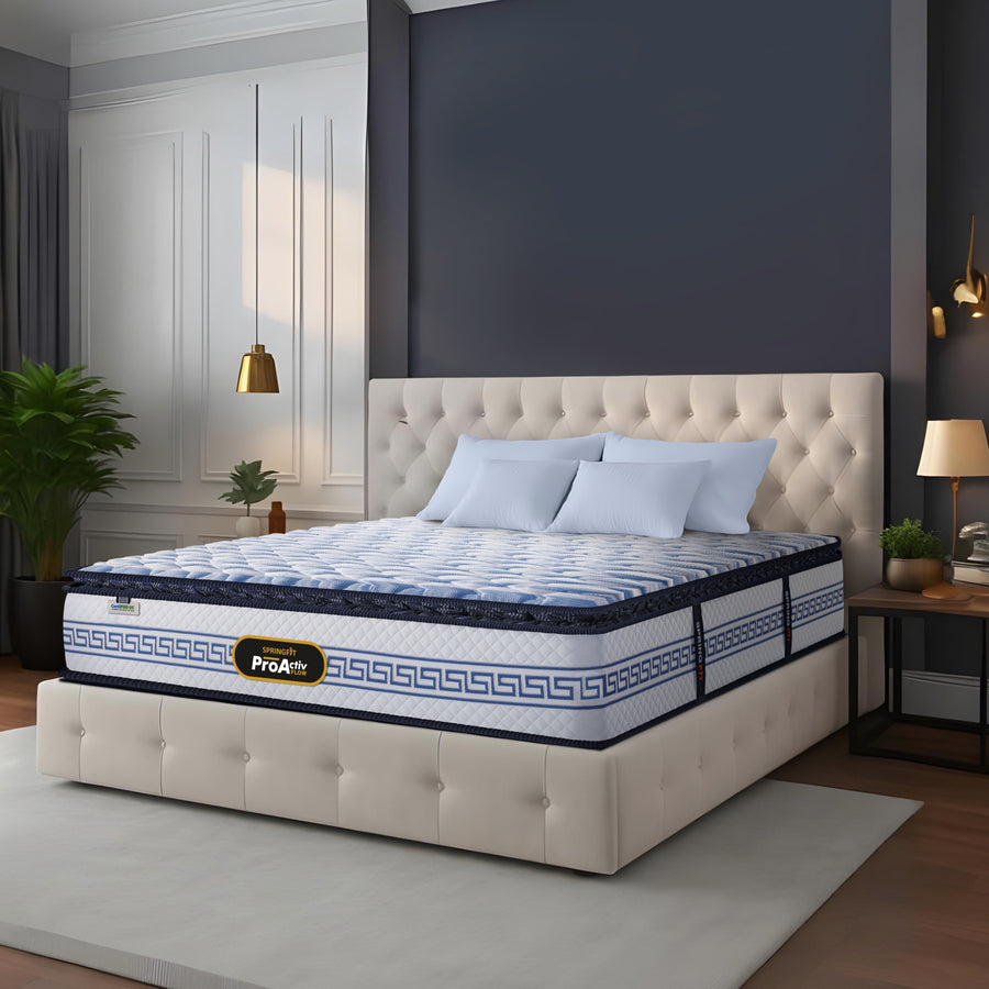 Springfit ProActiv Flow mattress on beige tufted platform bed in elegant navy and white bedroom with gold pendant lights, light blue pillows, and decorative plants