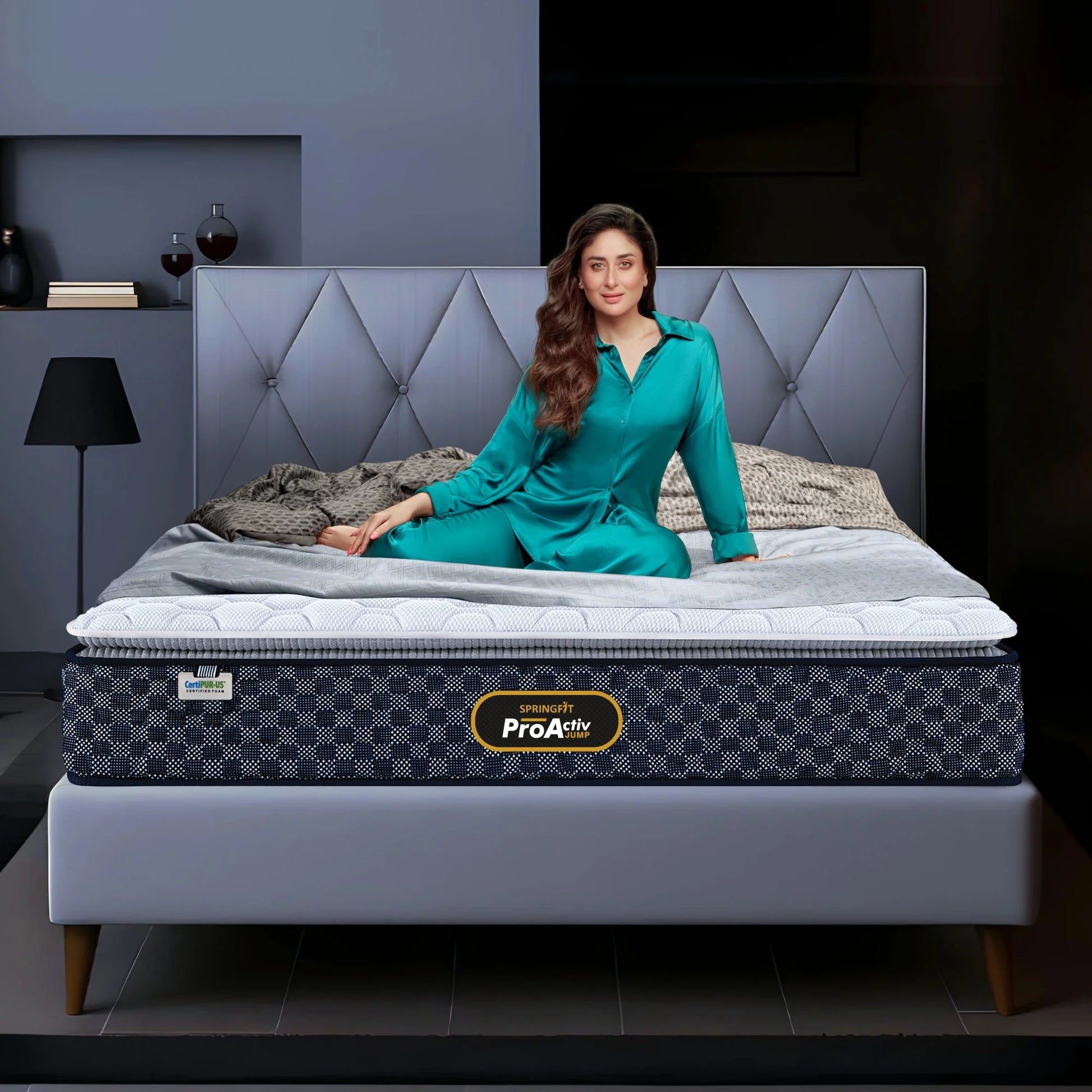 Springfit ProActiv Jump mattress lifestyle image with brand ambassador seated on bed with diamond tufted grey headboard in modern bedroom
