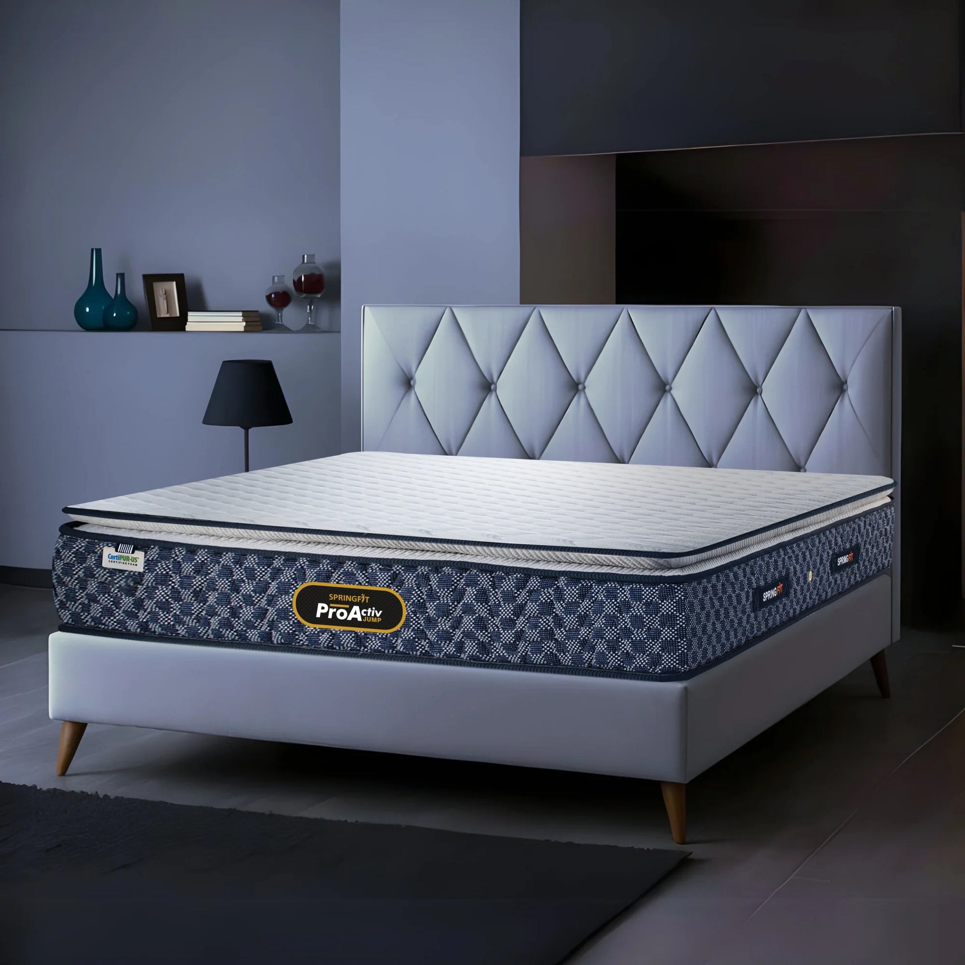 Springfit ProActiv Jump mattress on grey platform bed with diamond tufted headboard in blue-toned modern bedroom with side lamp