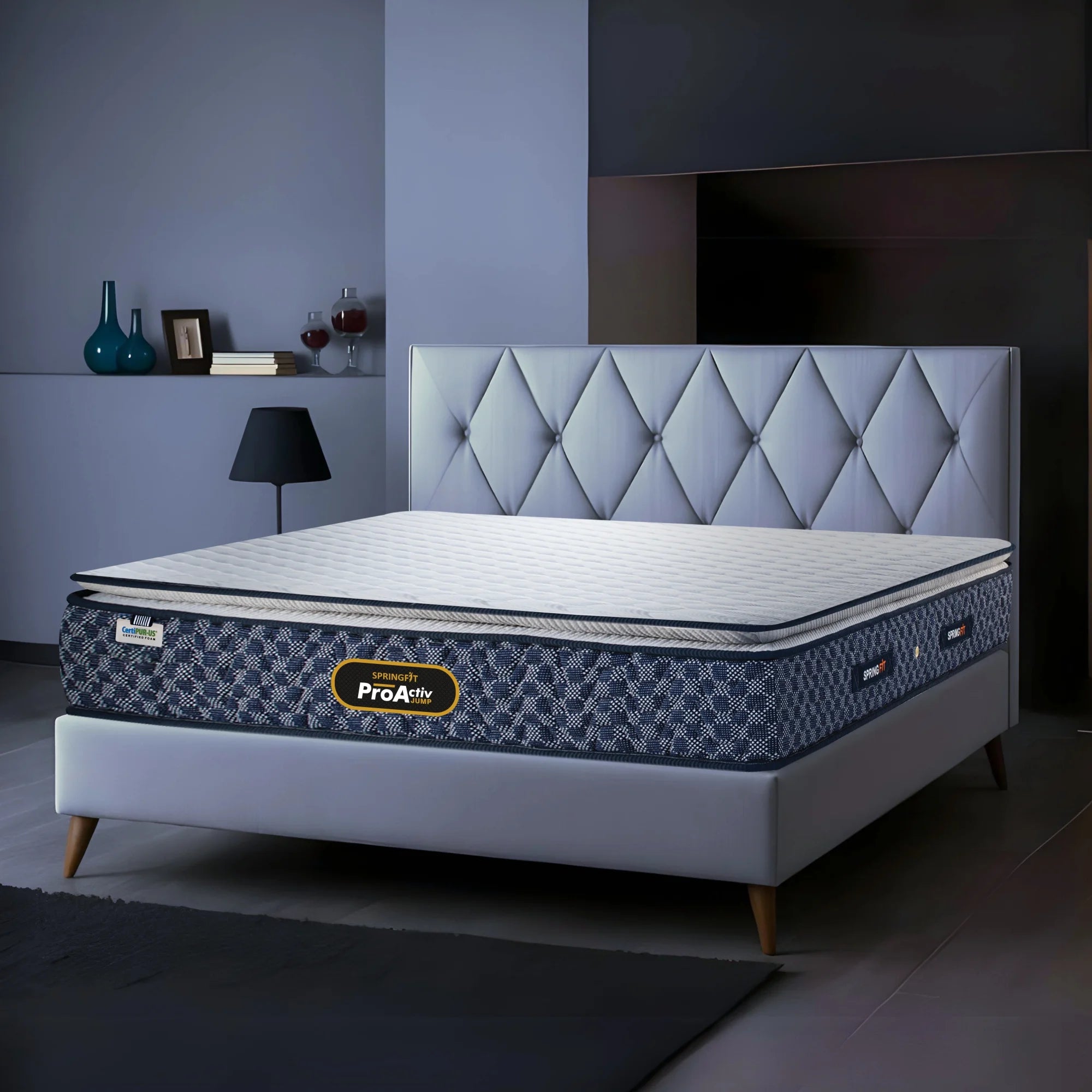 Springfit ProActiv Jump mattress on grey platform bed with diamond tufted headboard in blue-toned modern bedroom with side lamp