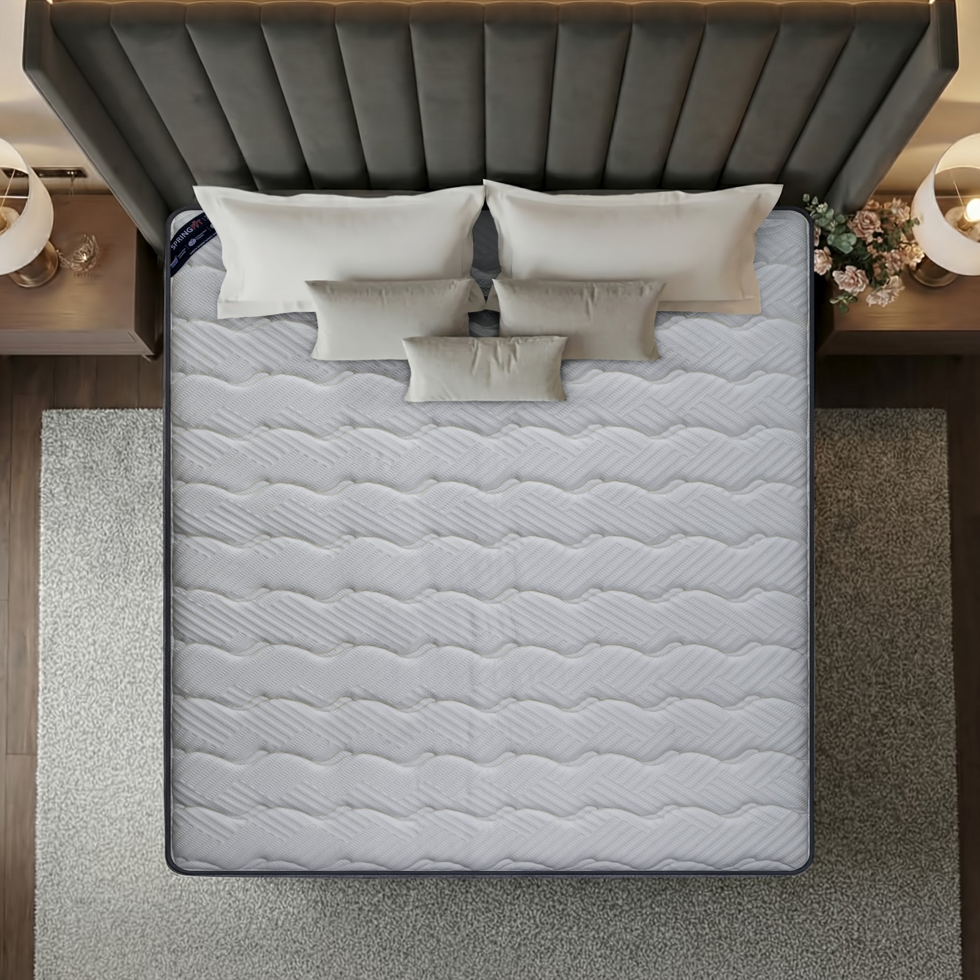 Overhead top-down view of the Springfit Reactive Classic mattress showing its full white wave-quilted fabric surface on a luxury bed with five layered cream pillows, flanked by globe pendant lamps and floral décor