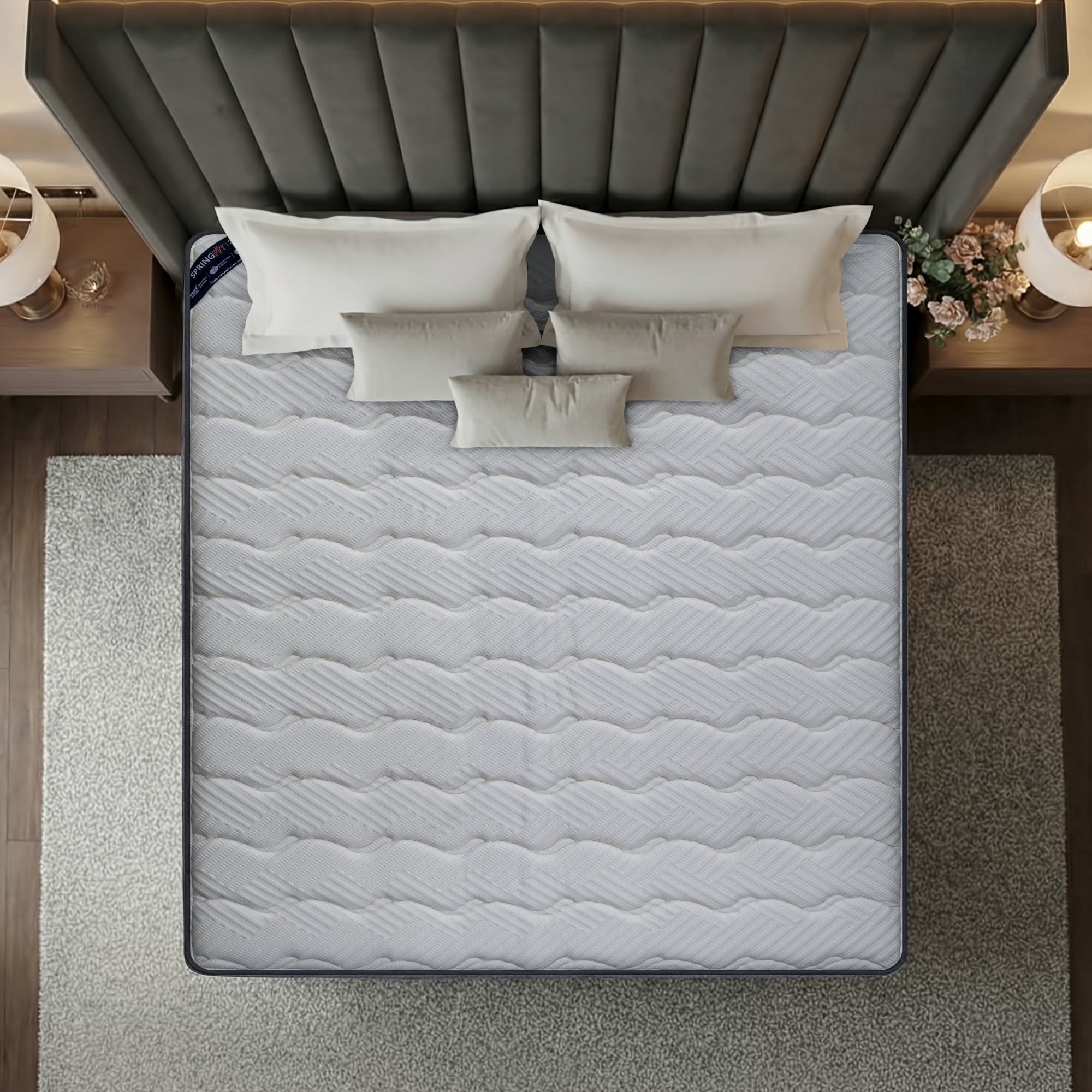 Overhead top-down view of the Springfit Reactive Classic mattress showing its full white wave-quilted fabric surface on a luxury bed with five layered cream pillows, flanked by globe pendant lamps and floral décor