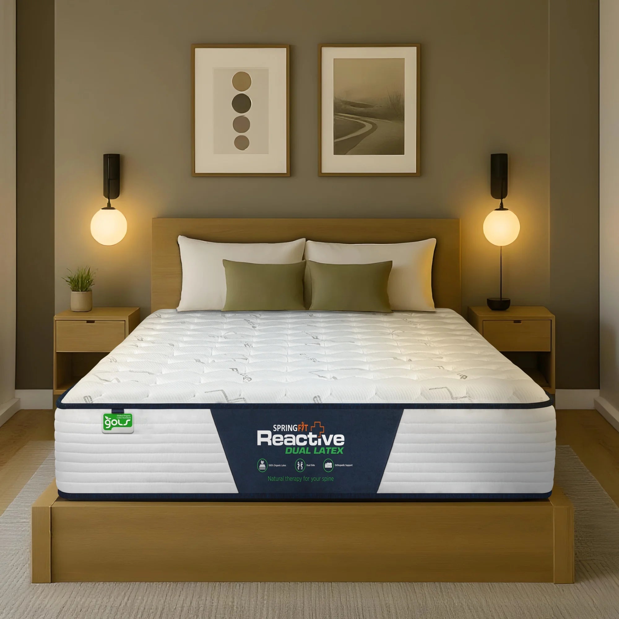 Front-facing view of the Springfit Reactive Dual Latex mattress with a white branded quilted top and navy piping, placed on a wooden platform bed in an olive-green bedroom with globe pendant lamps, olive cushions, and abstract wall art