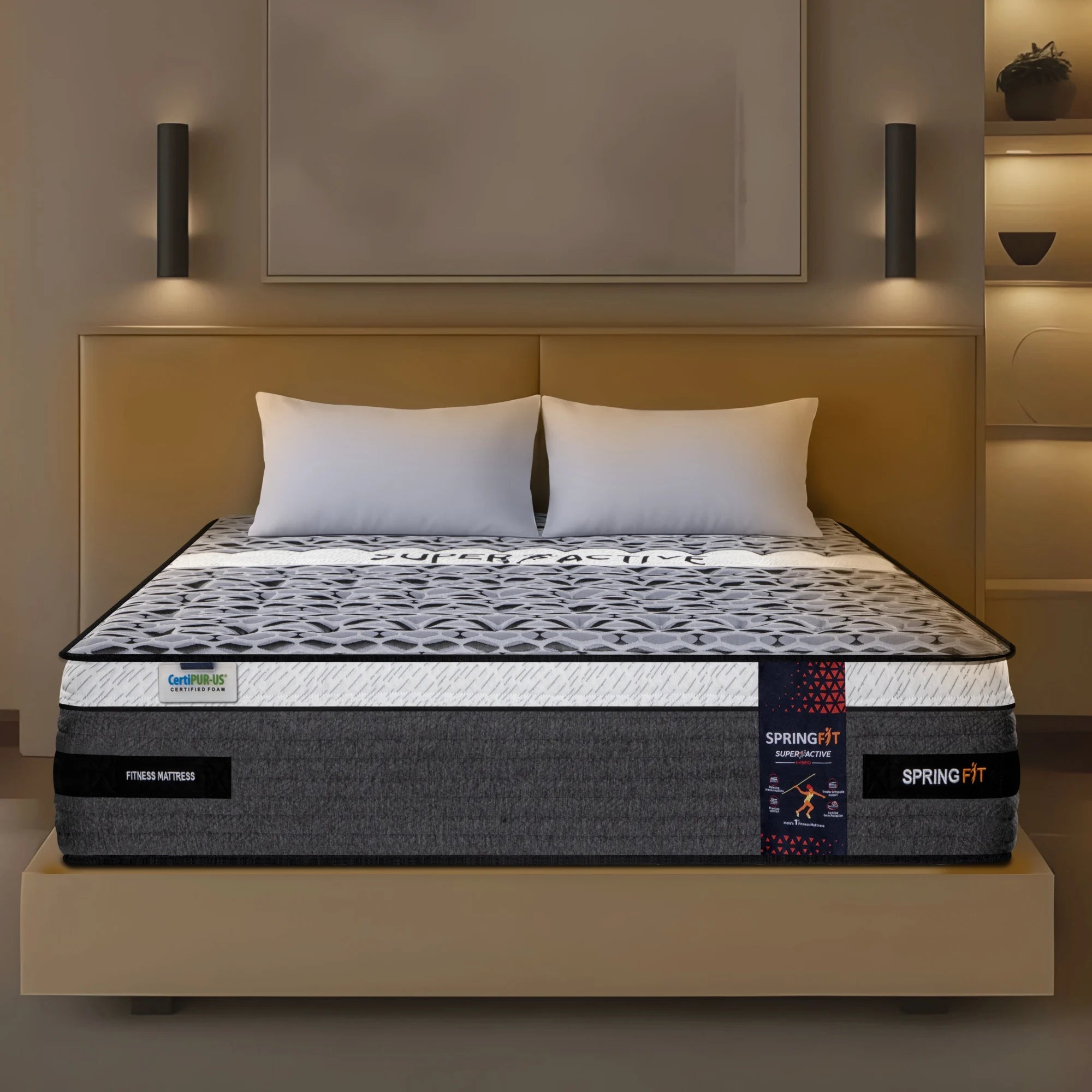 Front view of Springfit Super Active Hybrid fitness mattress with geometric dark fabric top on a beige platform bed with white pillows in a warm-toned bedroom