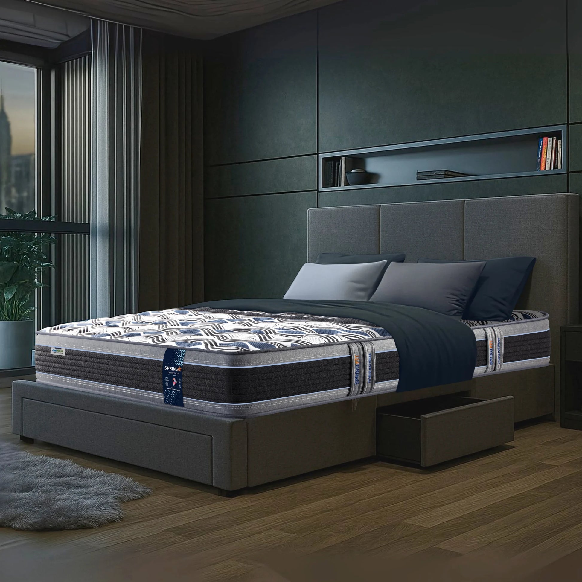 Angled lifestyle view of Springfit Super Active Renew mattress with wave-pattern fabric on a grey upholstered storage bed in a dark contemporary bedroom with city view