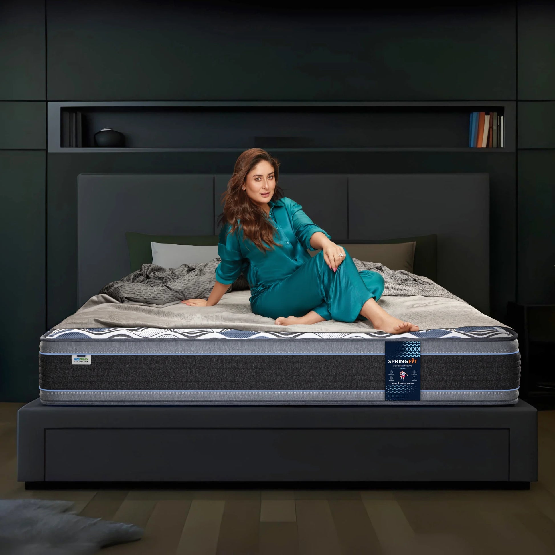 Springfit Super Active Renew mattress with CertiPUR-US certification on a dark platform bed with brand ambassador seated in a modern dark-toned bedroom