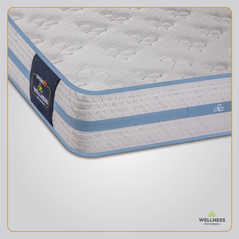 Close-up corner view of the Springfit Wellness Orthopedic mattress showcasing its quilted white fabric top, blue border tape, and Springfit brand label