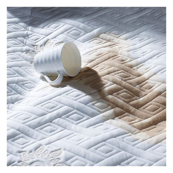 waterprWaterproof demonstration of Springfit mattress protector showing a tipped coffee cup with liquid spilling and beading on the quilted white surface without soaking throughoof mattress protector
